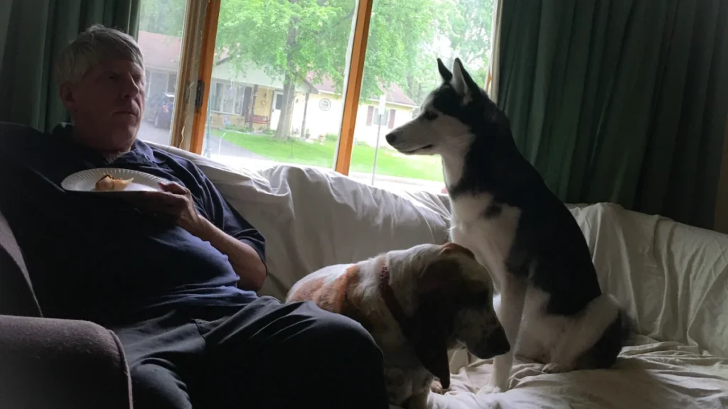 man with dog sitting bed home